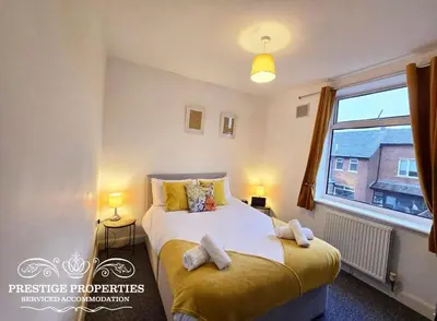 a bedroom with a bed and a large window at 8 Suffolk street by Prestige Properties SA in Barrow in Furness