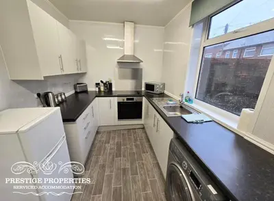 a kitchen with white cabinets and a black counter top at 8 Suffolk street by Prestige Properties SA in Barrow in Furness
