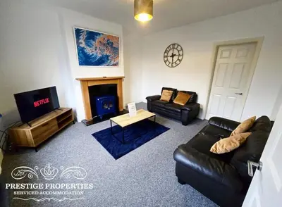 a living room with a black leather couch and a tv at 8 Suffolk street by Prestige Properties SA in Barrow in Furness