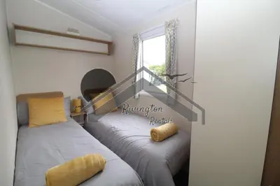 a bedroom with two beds and a window at Serenity - 8 Berth 3 Bedroom Static Caravan in Heysham