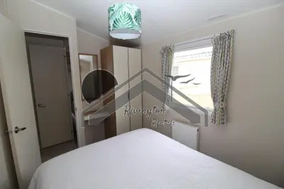 a bedroom with a white bed and a window at Serenity - 8 Berth 3 Bedroom Static Caravan in Heysham