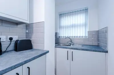 a kitchen with white cabinets and a sink and a window at LFC Football Apartment Anfield in Liverpool