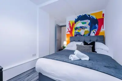 a bedroom with a large bed with a painting on the wall at LFC Football Apartment Anfield in Liverpool