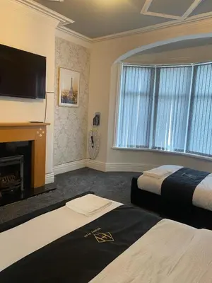 a hotel room with two beds and a flat screen tv at Holiday Plus - Holmfield Road in Blackpool