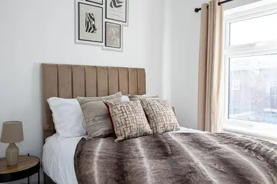 a bedroom with a large bed with pillows and a window at Deluxe Bolton Cinema House 2BR Modern Retreat with Free Parking in Bolton