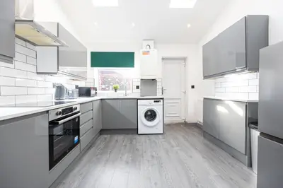 a white kitchen with a washing machine in it at Deluxe Bolton Cinema House 2BR Modern Retreat with Free Parking in Bolton
