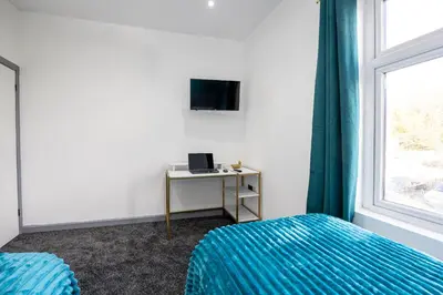 a bedroom with a bed and a desk and a window at Deluxe Bolton Cinema House 2BR Modern Retreat with Free Parking in Bolton