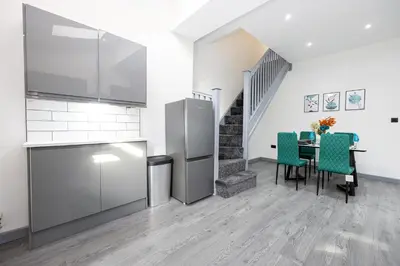 a kitchen with a table and chairs and a staircase at Deluxe Bolton Cinema House 2BR Modern Retreat with Free Parking in Bolton