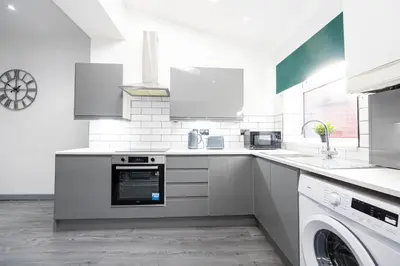 a white kitchen with a stove and a dishwasher at Deluxe Bolton Cinema House 2BR Modern Retreat with Free Parking in Bolton