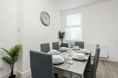 a dining room table with chairs and a clock on the wall at HORNSEY LODGE - Strictly NO Parties in Liverpool