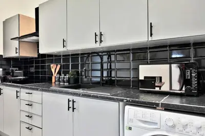 a kitchen with white cabinets and a microwave at Freckleton House in Town Centre, near Blackpool, Sleeps 6, Free Parking - By NMB Property in Kirkham