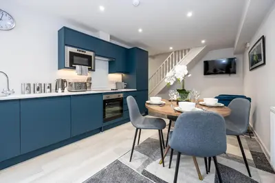 a kitchen and dining room with blue cabinets and a table and chairs at Morecambe Bay Free Parking Beach Front in Morecambe
