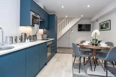 a kitchen with blue cabinets and a table with chairs at Morecambe Bay Free Parking Beach Front in Morecambe