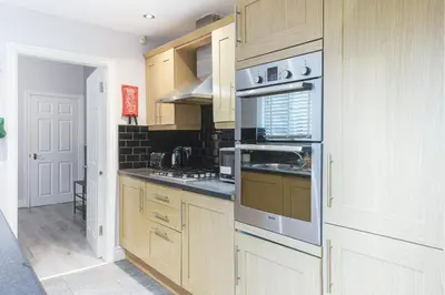 a kitchen with wooden cabinets and stainless steel appliances at Poppy's Project - July Road in Liverpool