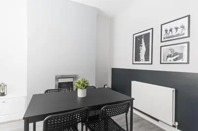 a dining room with a black table and chairs at Poppy's Project - July Road in Liverpool