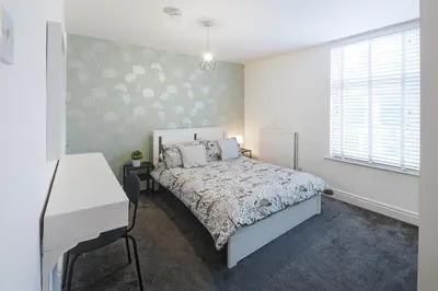 a bedroom with a bed and a desk and a window at Poppy's Project - July Road in Liverpool