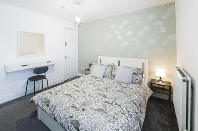 a bedroom with a large bed with a white bedspread at Poppy's Project - July Road in Liverpool