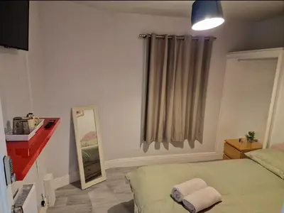 a bedroom with a bed and a mirror and a window at ArklesFCLiverpool in Liverpool