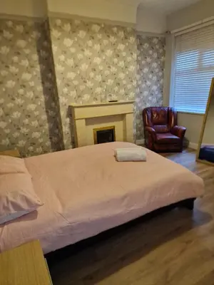 a bedroom with a bed and a fireplace and a chair at ArklesFCLiverpool in Liverpool