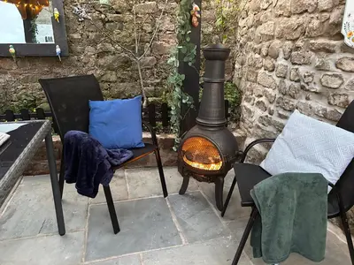 a patio with a stove and chairs and a blue pillow at Historical Village Cottage - Pet Friendly in Heysham