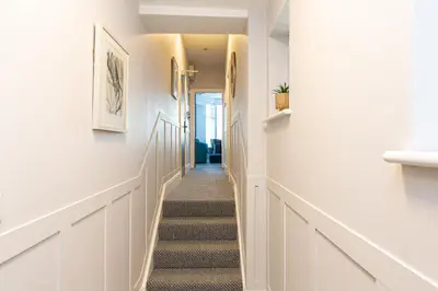 a hallway with stairs in a home with white walls at Stylish Seafront Apartment - Sleeps 6 - Gateway to the Lakes in Morecambe