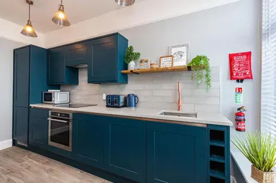 a kitchen with navy blue cabinets and white tiles at Stylish Seafront Apartment - Sleeps 6 - Gateway to the Lakes in Morecambe