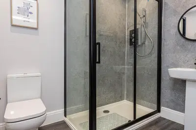 a bathroom with a shower with a toilet and a sink at Stylish Seafront Apartment - Sleeps 6 - Gateway to the Lakes in Morecambe