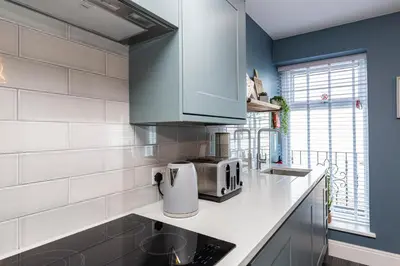 a kitchen with blue walls and white counter tops at Seafront Apartment - Sleeps 6 - Gateway to the Lake District - Brand New in Morecambe