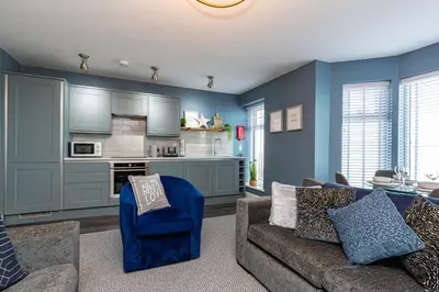 a living room with a couch and a kitchen at Seafront Apartment - Sleeps 6 - Gateway to the Lake District - Brand New in Morecambe