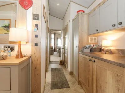 a kitchen with wooden cabinets and a hallway at Pine Lake View in Carnforth