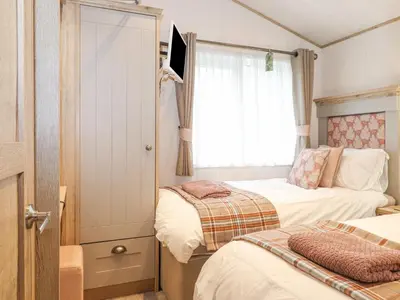a small bedroom with two beds and a window at Pine Lake View in Carnforth