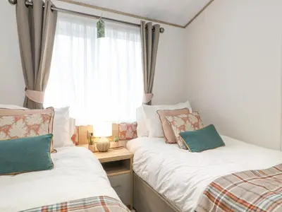 two beds in a small room with a window at Pine Lake View in Carnforth