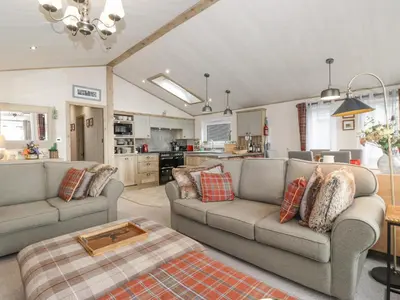 a living room with two couches and a kitchen at Pine Lake View in Carnforth