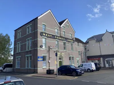 a building on a street with cars parked in a parking lot at Apartment 1 West County by Prestige Properties SA in Millom