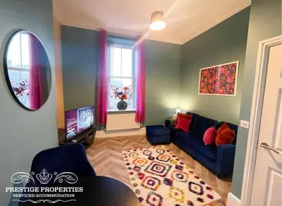 a living room with a blue couch and a television at Apartment 1 West County by Prestige Properties SA in Millom