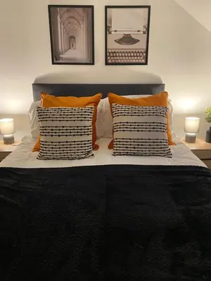 a bed with orange and white pillows on it at Stylish Apartments near the sea front at Morecambe in Heysham