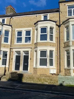 a brick building with white windows on a street at Stylish Apartments near the sea front at Morecambe in Heysham