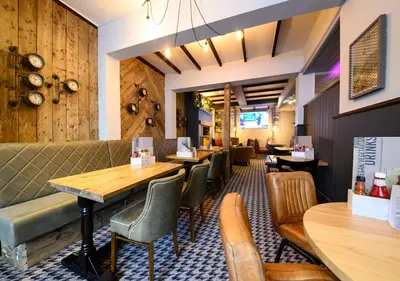 a restaurant with wooden tables and chairs in a room at The County Hotel by Innkeeper's Collection in Lytham St Annes