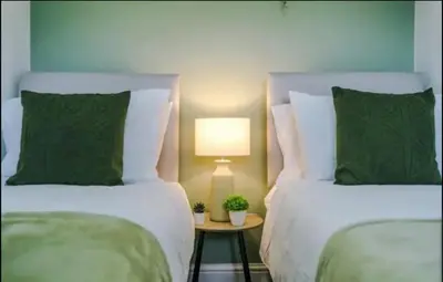 a bedroom with two beds and a table with a lamp at St Helens - Cosy 1 Bed in Saint Helens