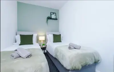 two beds in a room with green and white at St Helens - Cosy 1 Bed in Saint Helens