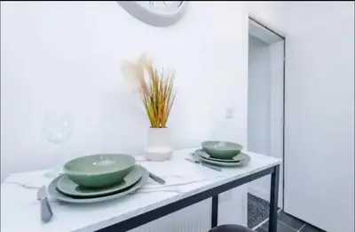 a table with two green bowls and plates on it at St Helens - Cosy 1 Bed in Saint Helens