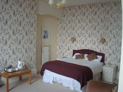 a bedroom with a large bed with floral wallpaper at The North Euston Hotel in Fleetwood