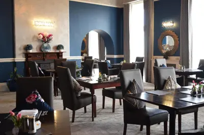 a restaurant with blue walls and tables and chairs at The North Euston Hotel in Fleetwood