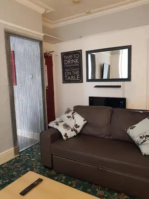 a living room with a brown couch and a mirror at Somerset House Apartments in Blackpool