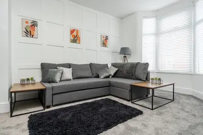 a living room with a gray couch and two tables at HARROW LODGE - Strictly NO Parties in Liverpool