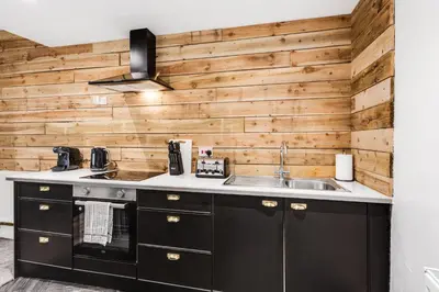 a kitchen with black cabinets and a wooden wall at HARROW LODGE - Strictly NO Parties in Liverpool