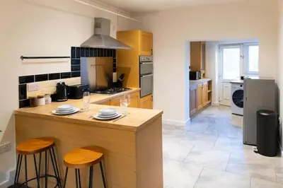 a kitchen with a counter and two stools at Modern cottage WiFi Free Parking in Penwortham
