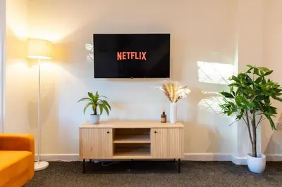 a living room with a tv on a wall with plants at Modern cottage WiFi Free Parking in Penwortham