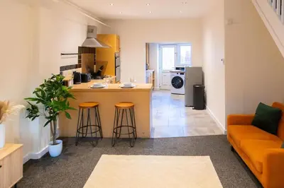 a kitchen and living room with a counter and stools at Modern cottage WiFi Free Parking in Penwortham
