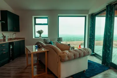 a living room with a couch and large windows at The Wellsprings Lodges and Restaurant in Clitheroe